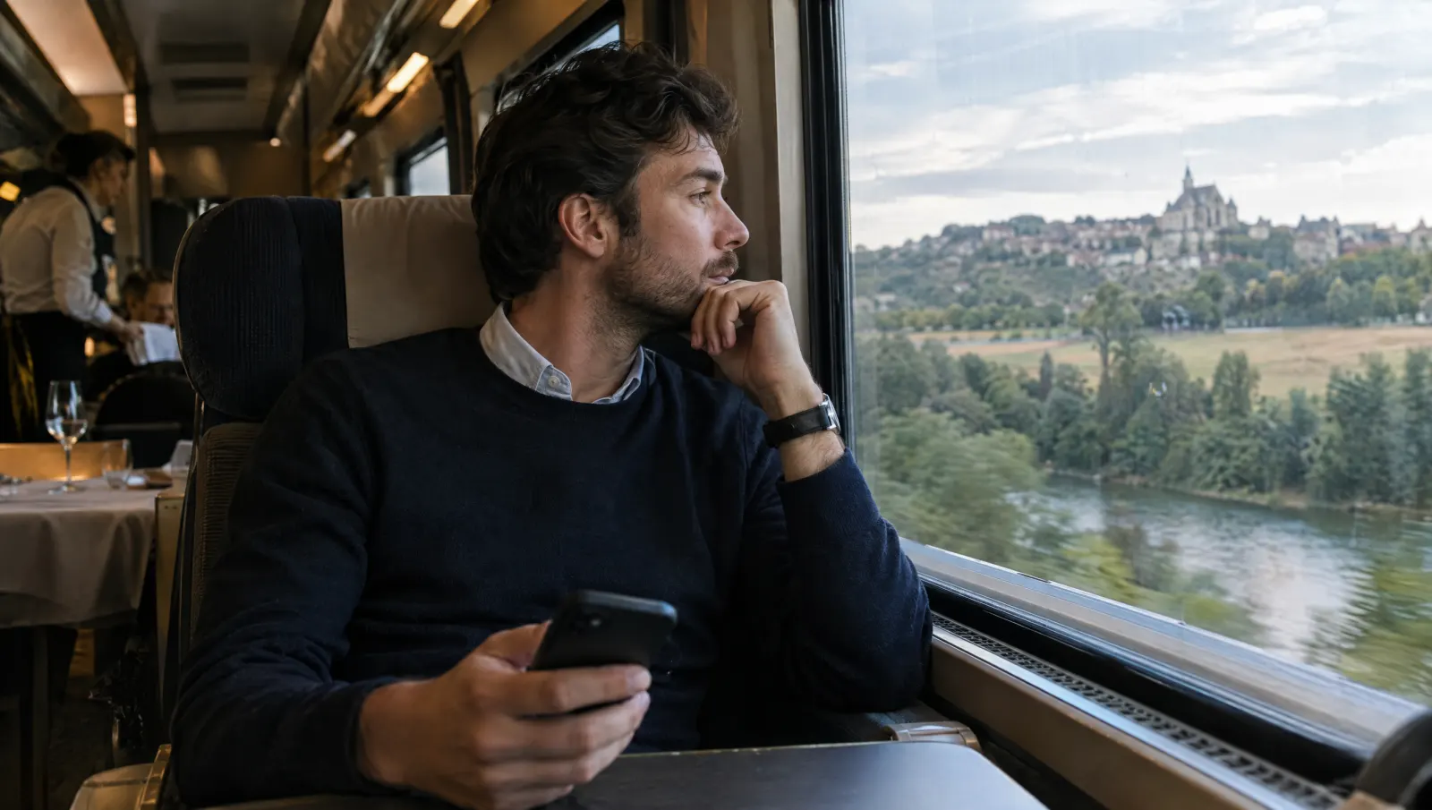 En déplacement, le dirigeant regarde par la fenêtre, téléphone en main